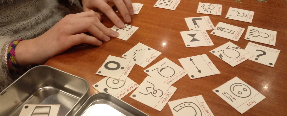 Sur une table, quelques pictogrammes carrés, manipulés par une utilisatrice.